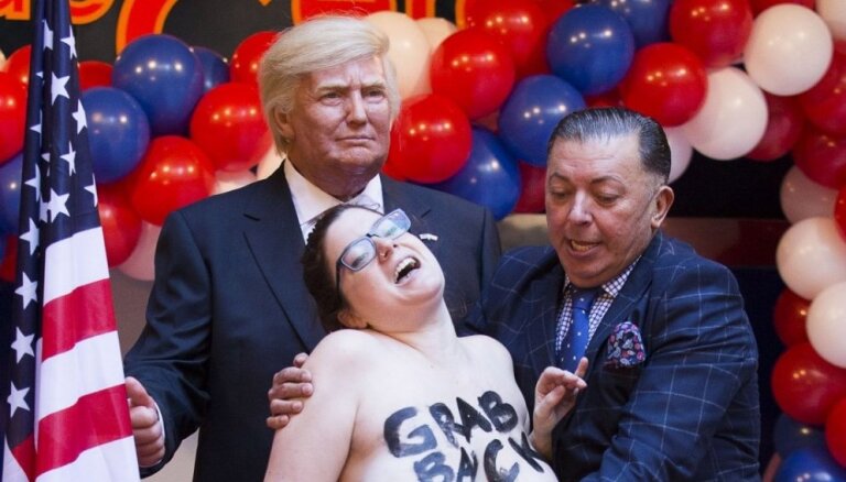 Meitene kailām krūtīm uzklūp vaska Donaldam Trampam